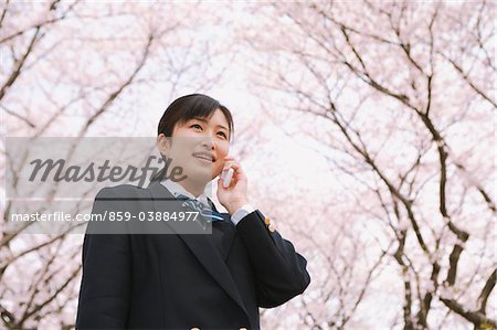 High School Girl Listening To Phone Under Blooming Tree