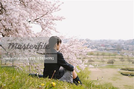 High-School-Mädchen sitzen unter Blossom Kirschenbaum