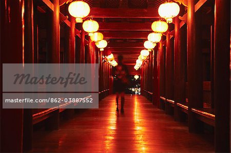 Woman walking on replica of traditional Dong minority bridge at Folk Culture Village, Shenzhen, Guangdong, China