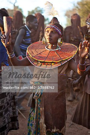 During a Ngetunogh ceremony, the mother of a Pokot initiate sings and dances holding high the cowhorn container she used to smear fat over the masks of her son and other boys as a blessing.