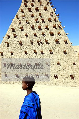 Boy walking along the Sankore mosque, a UNESCO World Heritage Site. Timbuktu, Mali, West Africa