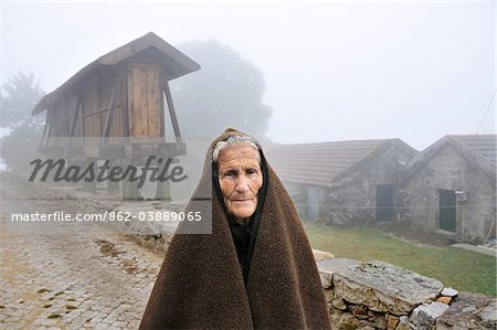 Woman of Paredes do Rio, in Peneda Geres National Park, Tras os Montes, Portugal. In the background, a 'espigueiro', traditional granary of this region.