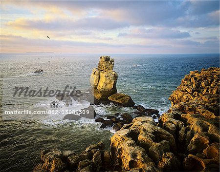 Nau dos Corvos and Carvoeiro cape, at sunset, with fishing boats going to work. On the horizon we can see the Berlengas islands, Portugal