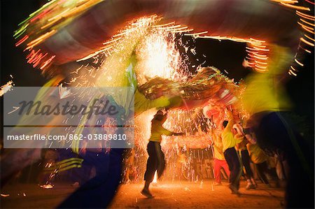 Thailand, Ko Phuket, Phuket.  Dragon dancers and fireworks during the Phuket Vegetarian Festival.  The 9 day religious festival celebrates spiritual and body cleansing for the local Chinese community.