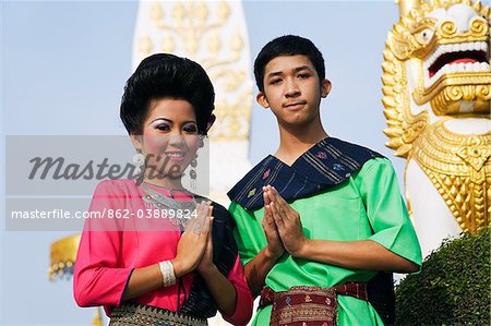 Thailand, Nakhon Phanom, That Phanom.  Dancers in ceremonial Isan dress with the chedi at Wat Phra That Phanom in the background.  The dancers perform traditional folk dances to pay religious homage during the festival of Ok Phansa (usually in October).