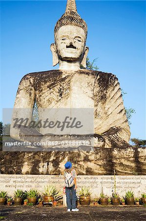 Thailand, Nong Khai, Nong Khai.  A tourist looks up at a giant sculpture in the Sala Kaew Ku Sculpture Park.