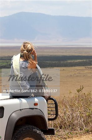 Tanzania, Ngorongoro. A tourist looks out over the Ngorongoro Crater from the bonnet of her Land Rover.