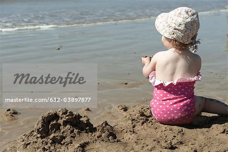 Fille enfant en bas âge jouer dans le sable à la plage, vue arrière
