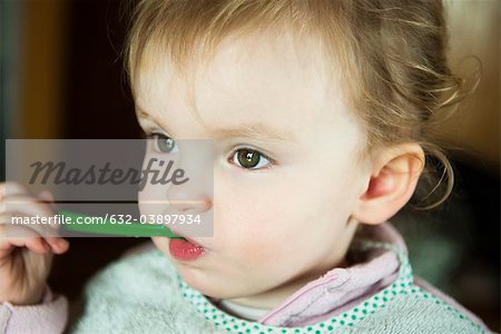 Toddler girl feeding herself, portrait