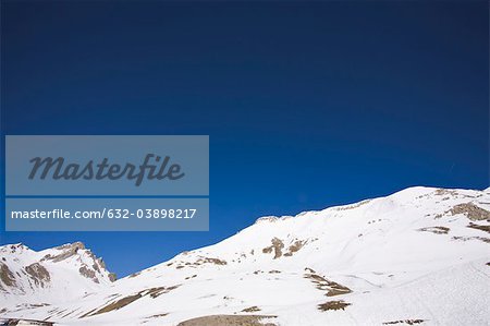Snow-covered mountain against clear blue sky