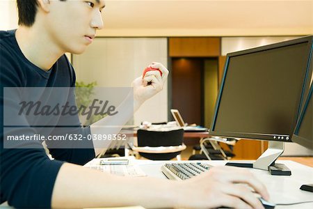 Office worker using computer, squeezing stress ball with one hand