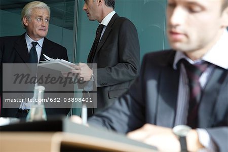 Exekutive in Diskussion, junge Unternehmer arbeiten im Vordergrund