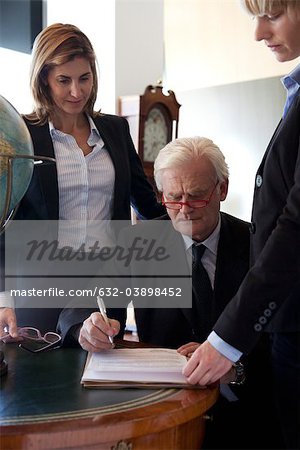 Executive examining documents, colleagues by his side