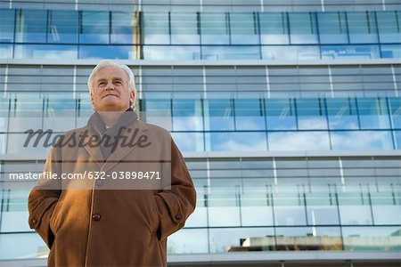 Mature man standing in front of building, looking away, portrait