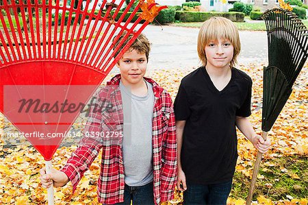 Two boys holding rakes