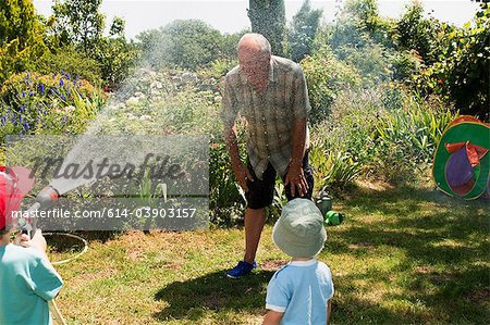 Petits-fils, grand-père de pulvérisation avec tuyau d'arrosage