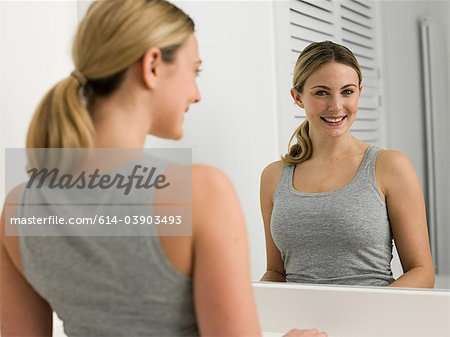Reflet de la jeune femme au miroir de salle de bains
