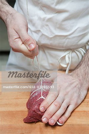 Butcher tying beef tenderloin with string