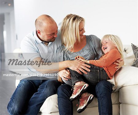 Un famille souriant assis dans un divan, Suède.