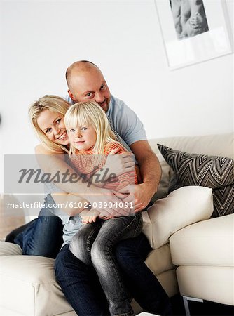 Un famille souriant assis dans un divan, Suède.