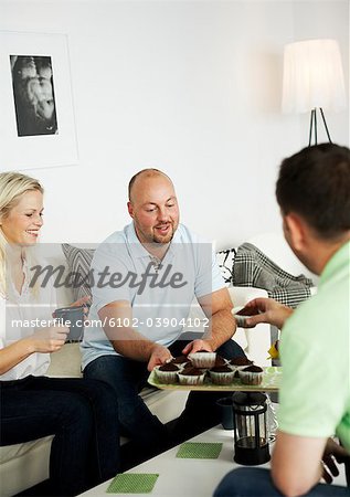 A woman and two men having a cup of coffee together, Sweden.
