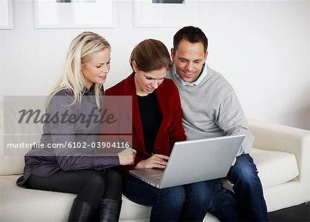 Three people using a laptop, Sweden.