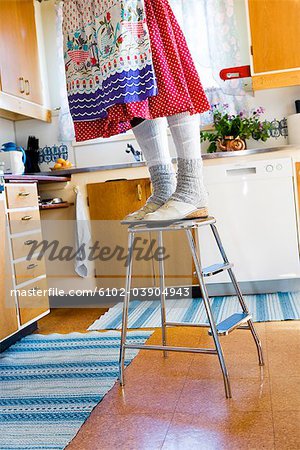 Woman standing on a stool in a kitchen, Sweden.