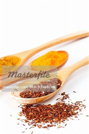 Detail of spices in the spoons with shadow over a white background