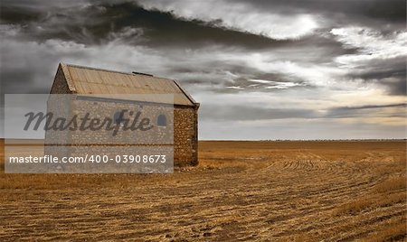 An old farm building surrounded by dark clouds