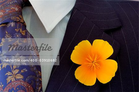 Close-up of a bright buttonhole flower on a businessman's pinstripe suit, contrasting with the flower on his tie.
