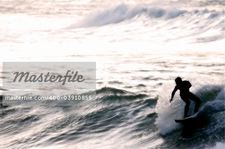 Surfer silhouetted through sea mist just after sunset