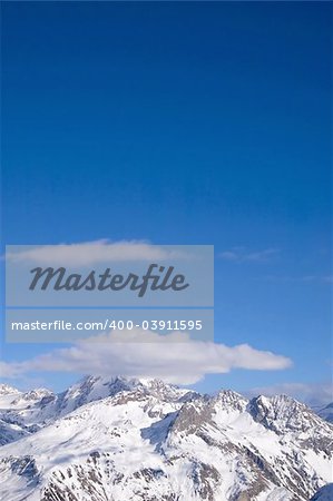 snowed peak of a mountain surrounded by small cloud, a lot of blue for copy-space