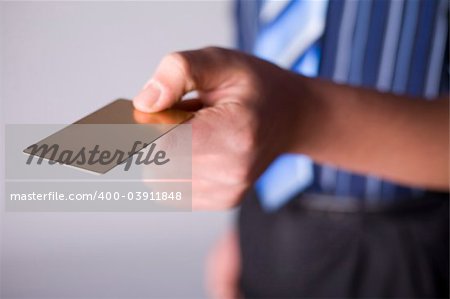 Man's hand holding gold credit card. Focus on the card. Body unfocus.