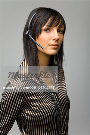 Young woman with telephone headset, isolated on grey background in studio