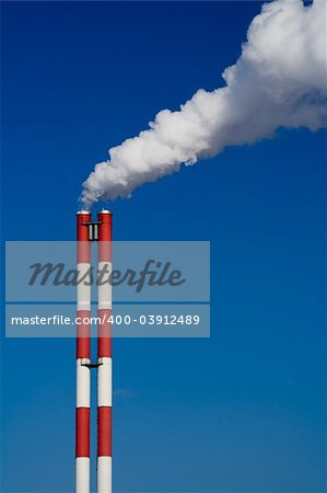 The chimney of a factory with white smoke. Vertical