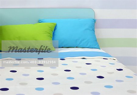 Bed with bright blue and green linen - home interiors