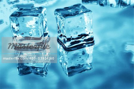 Blue toned ice cubes on reflective surface