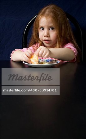 Redheaded girl eating orange by the black table