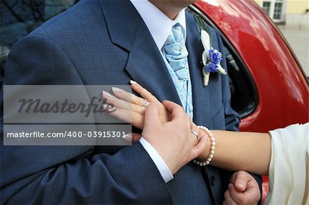 The hands of the bride and the groom on his heart