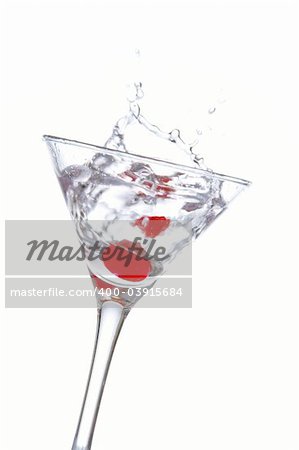 Two red cherrys splashing into a cocktail glass