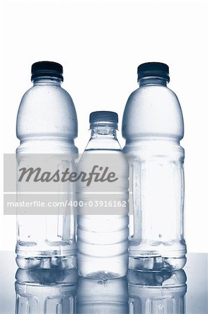 Three bottles of mineral water with droplets reflecting on white background