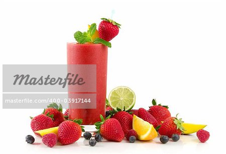 A glass of strawberry smoothie surrounded by fresh fruits