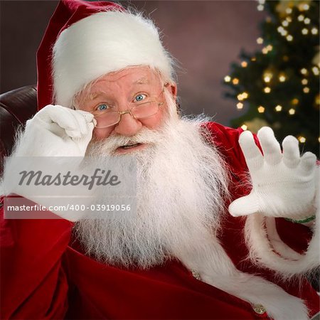 Santa Claus, waist up, indoor studio shot, christmas decoration in background, waving hand, focus on foreground