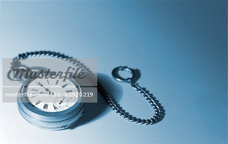 Old silver pocket watches on a chain; on a white background; focused on dial; picture tinted blue