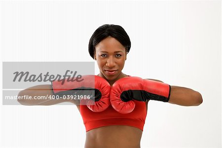 African American young adult woman wearing boxing goves with fists together.