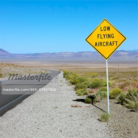 Low flying aircraft sign alongside desloate highway.