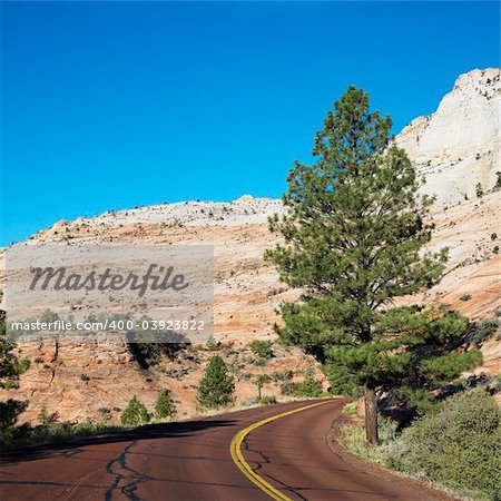 Two lane road winding along desert cliffs in Zion National Park, Utah.