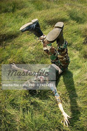 Attractive tattooed Caucasian woman in camouflage lying on grass with her legs up in the air in Maui, Hawaii, USA.