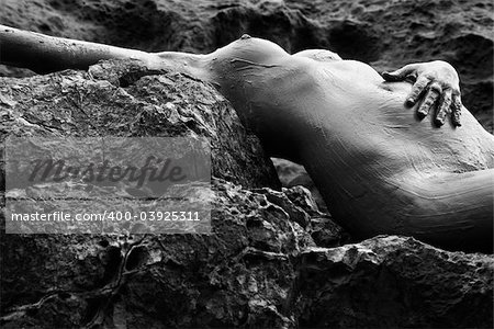 Young adult Caucasian female nude lying on rocky coast of Maui, Hawaii.