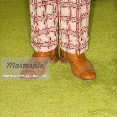 Close-up of Caucasian male legs in plaid pants standing on green retro carpet.